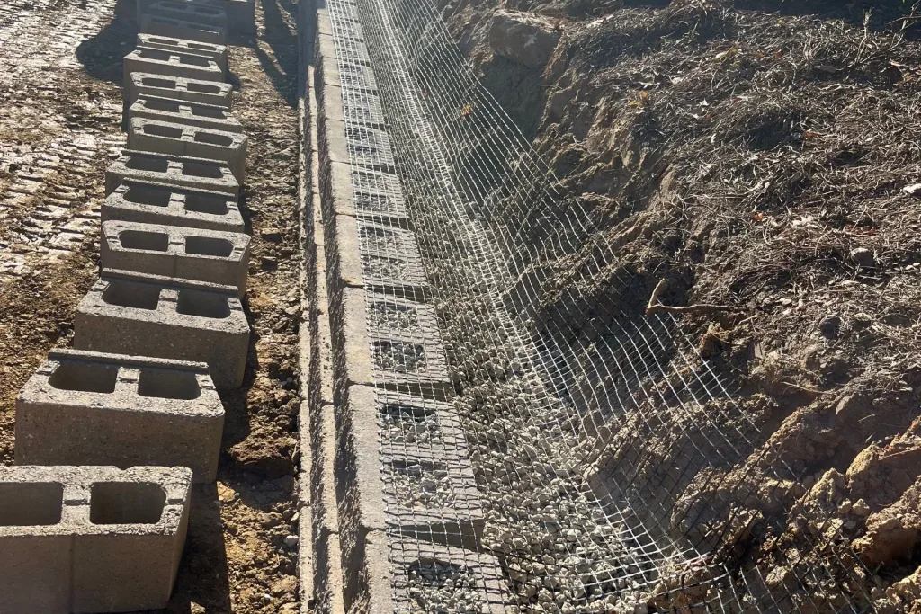 Retaining wall with backfill, drainage pipe, and geogrid