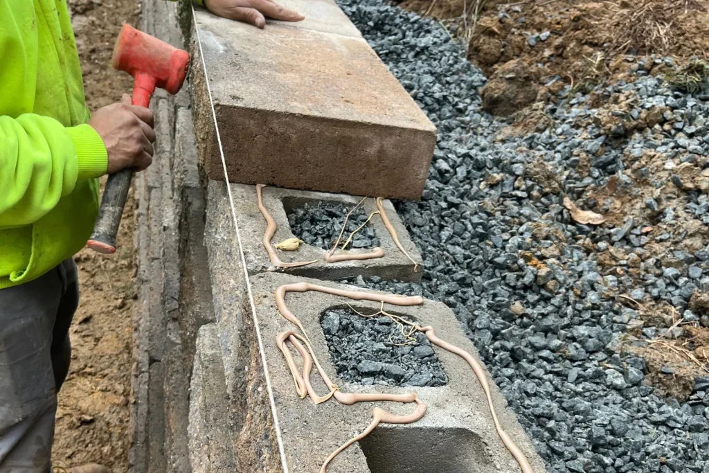 Retaining wall with cap stones aligned and secured, final backfill added, and topsoil applied.
