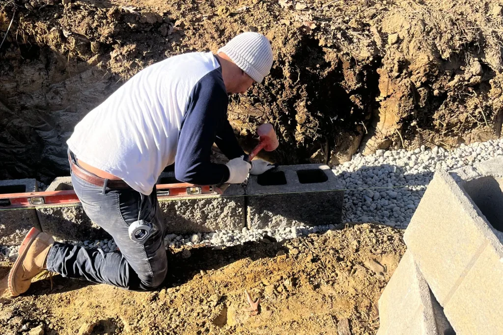 layer of compacted 57 stone being laid as the base for a retaining wall